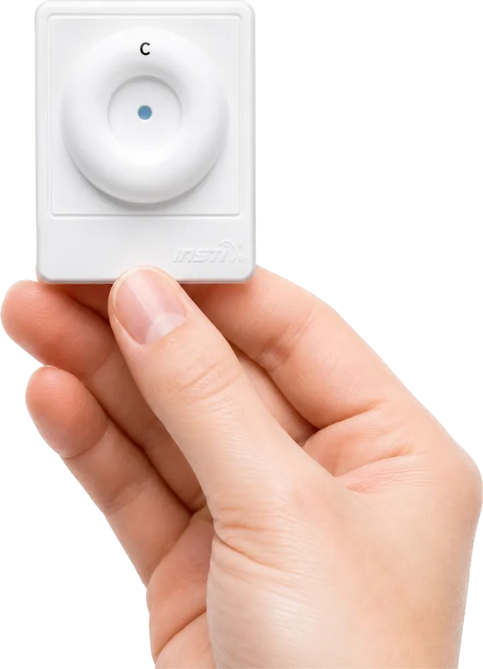 A hand holding the INSTI HIV Self Test device showing a clear result